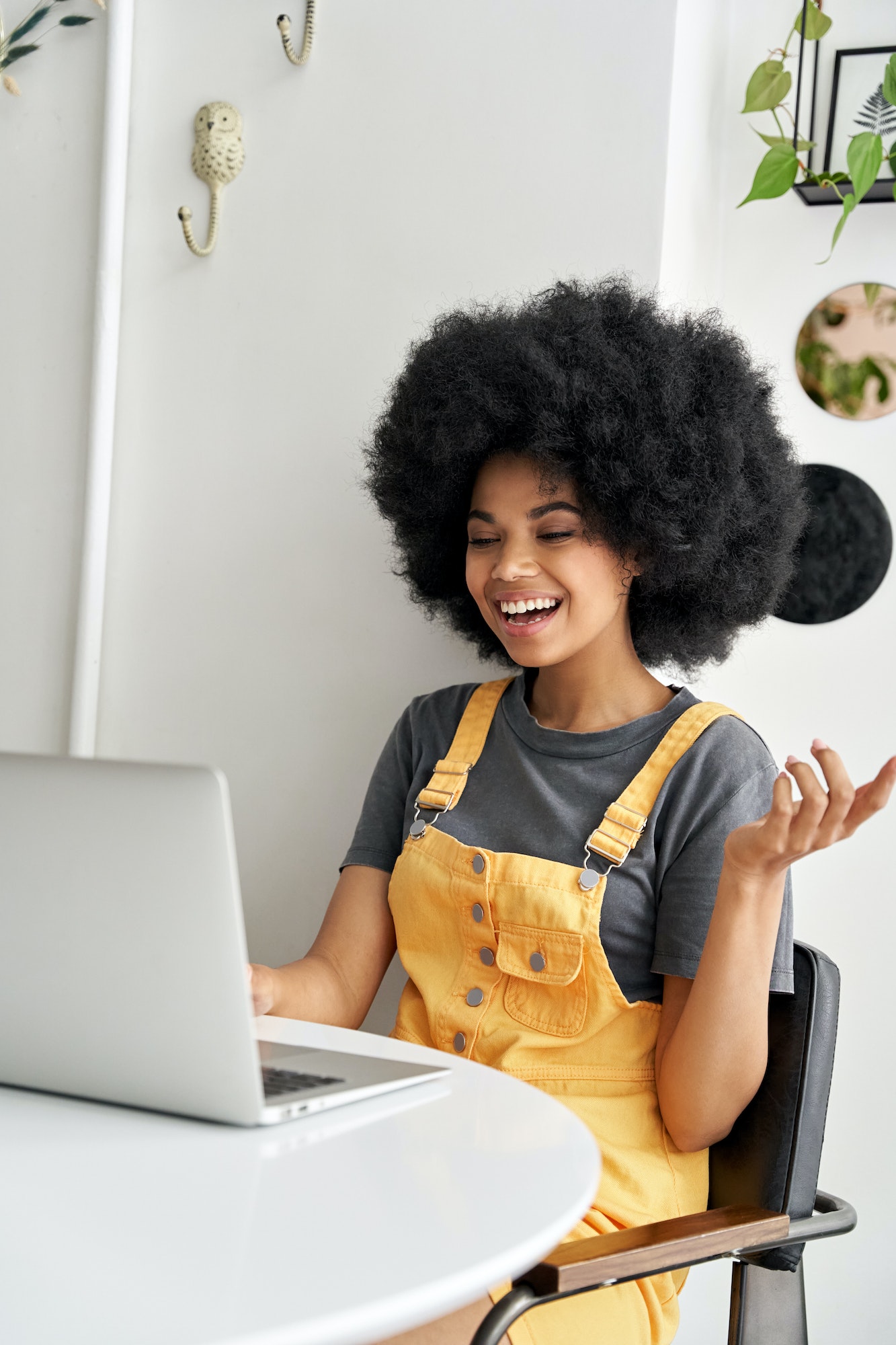 Happy African lady using laptop video conference calling friend in cafe.