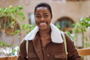 Happy, portrait and black woman student at college standing in an outdoor garden in South Africa. H